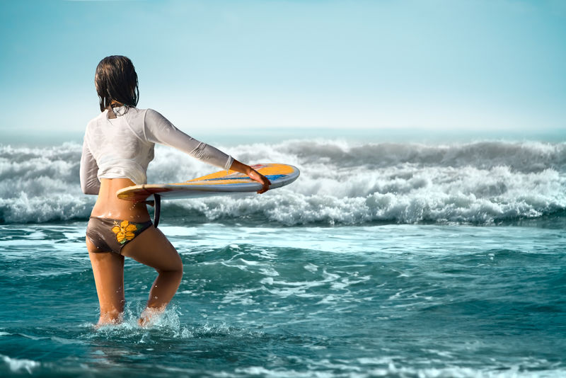 性感的女孩在巴厘海滩冲浪板的冲浪