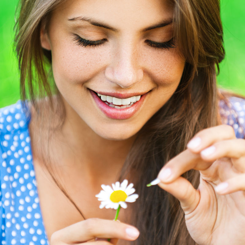 年轻可爱的微笑着的女人在花上惊奇-撕开花瓣-特写镜头