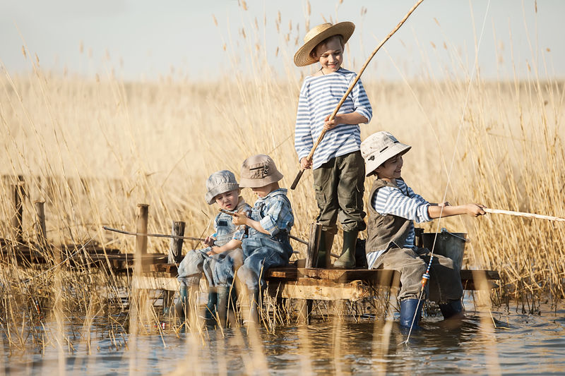 四个小男孩在湖边日落时钓鱼