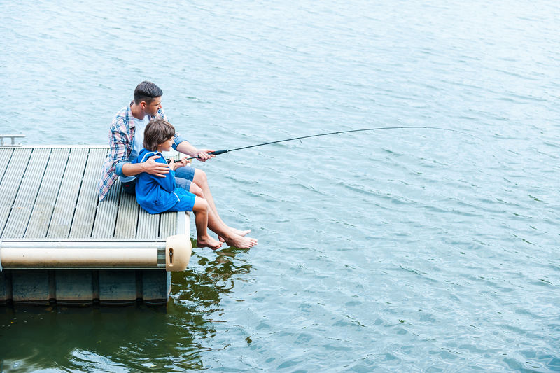 父子钓鱼-爸爸和儿子在码头边钓鱼的俯视图