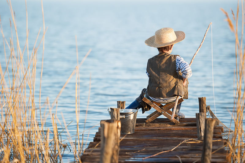 小男孩日落时在湖边钓鱼
