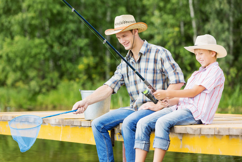 父亲和儿子坐在桥上钓鱼