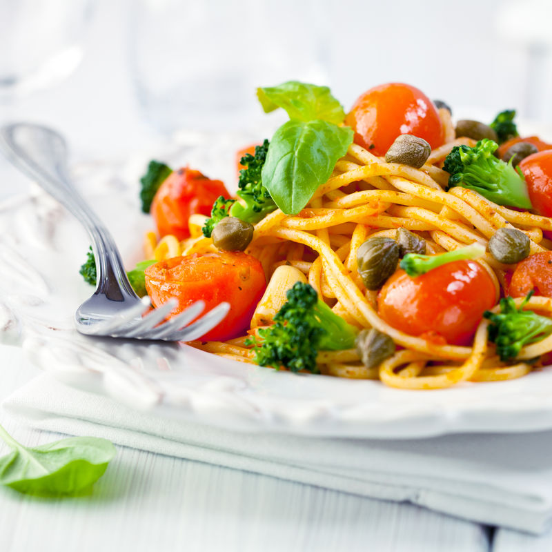 意大利面与樱桃番茄-花椰菜-刺山柑和新鲜罗勒的特写镜头-意大利菜-意大利菜-自制食物-象征性的形象-美味素菜的概念-闭合