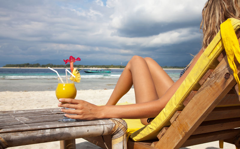 在热带海滩上享受鸡尾酒的女人