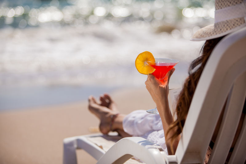 一位年轻女子在海滩上喝着冰镇马提尼放松的特写镜头