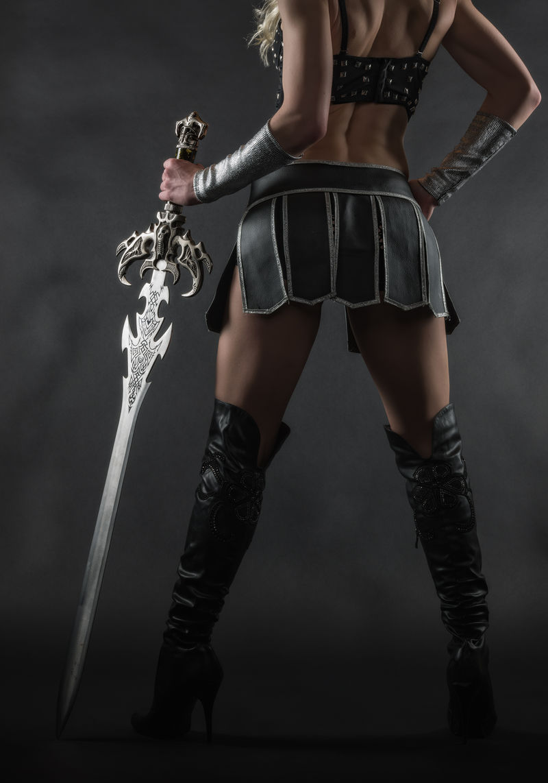 身着性感服装手持宝剑背景灰蒙蒙的表演者女性