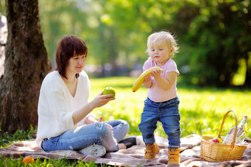 美丽的年轻女子和她可爱的小儿子在阳光公园野餐