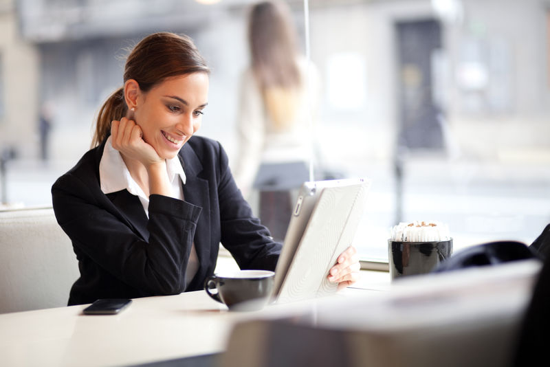 快乐的年轻女商人在咖啡馆使用平板电脑-选择性聚焦