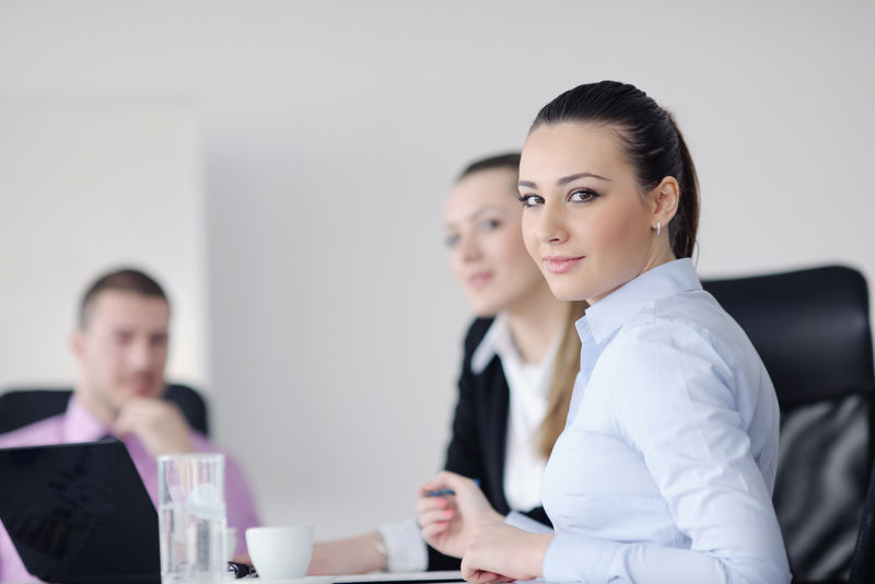 成功的商业女性与她的员工站在现代明亮办公室的背景下