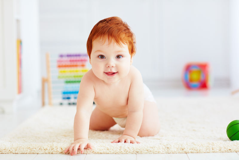可爱的快乐婴儿在家里的地毯上爬行的照片