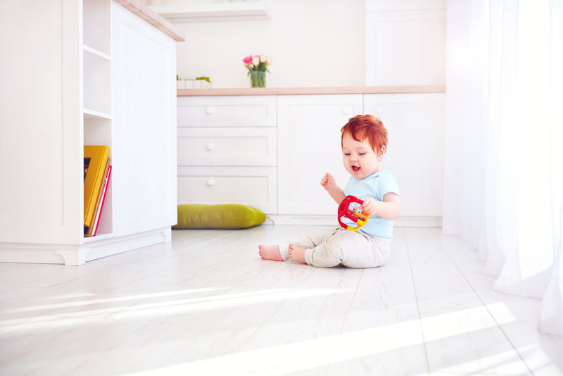 可爱的姜黄色小男孩在明亮的厨房玩玩具，在家里。