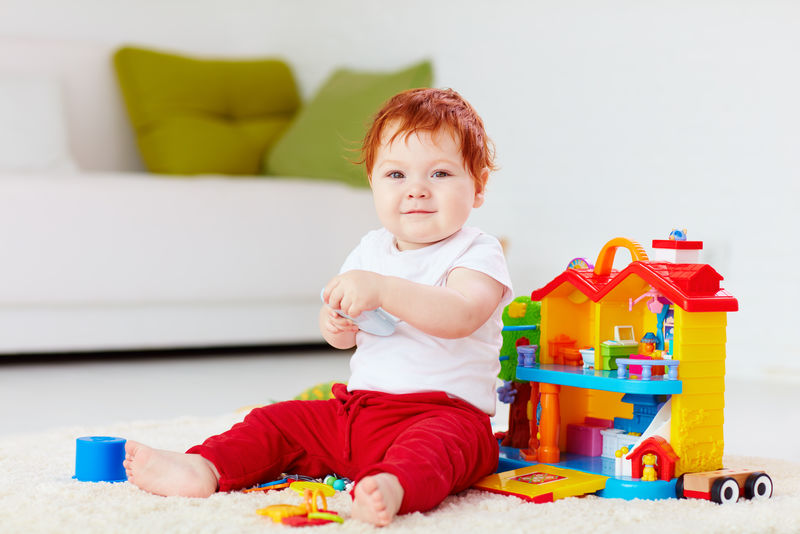 可爱的红头发婴儿在家玩玩具