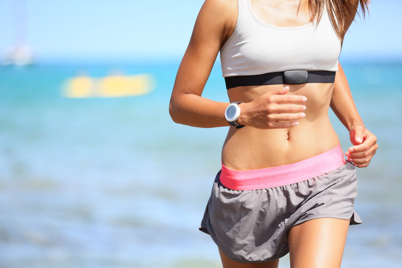 跑步的女人-心率监视器-在沙滩上跑步-戴着手表和运动胸罩-适合女性健身模式的户外健身锻炼和夏日健身生活的一部分