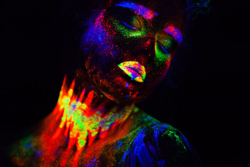 在霓虹灯下美丽的外星模特。这是一幅荧光彩妆的美丽模特的肖像画，是一幅女性在紫外光下摆姿势、彩妆的艺术设计。黑底隔离