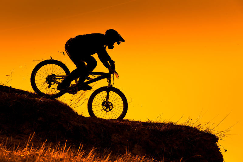 日落时下坡山地自行车骑行的轮廓