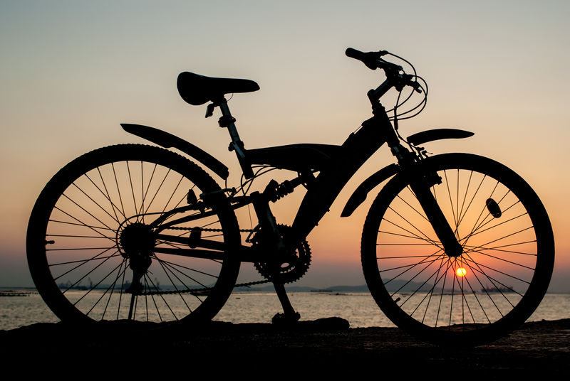 日落天空背景下海边码头山地自行车停车场轮廓图