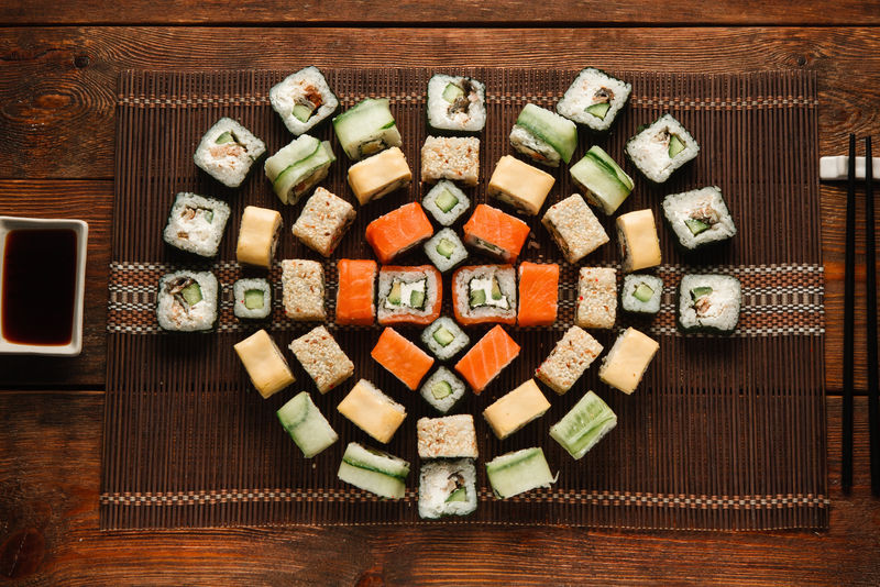 日本美味新鲜的一套彩色寿司卷，铺在棕色草席上，平放。美食艺术，精美装饰，豪华餐厅菜单照片。
