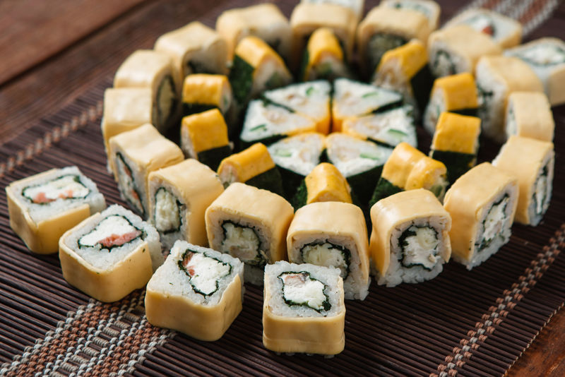 美味的五颜六色美味的寿司卷，放在草席上，特写。日本豪华餐厅菜单照片，传统海鲜。
