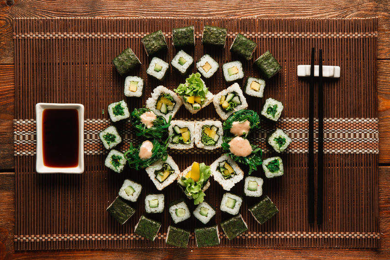 素食寿司卷装饰精美，放在棕色草席上，平放。日本传统美食、美食艺术、烹饪杰作。