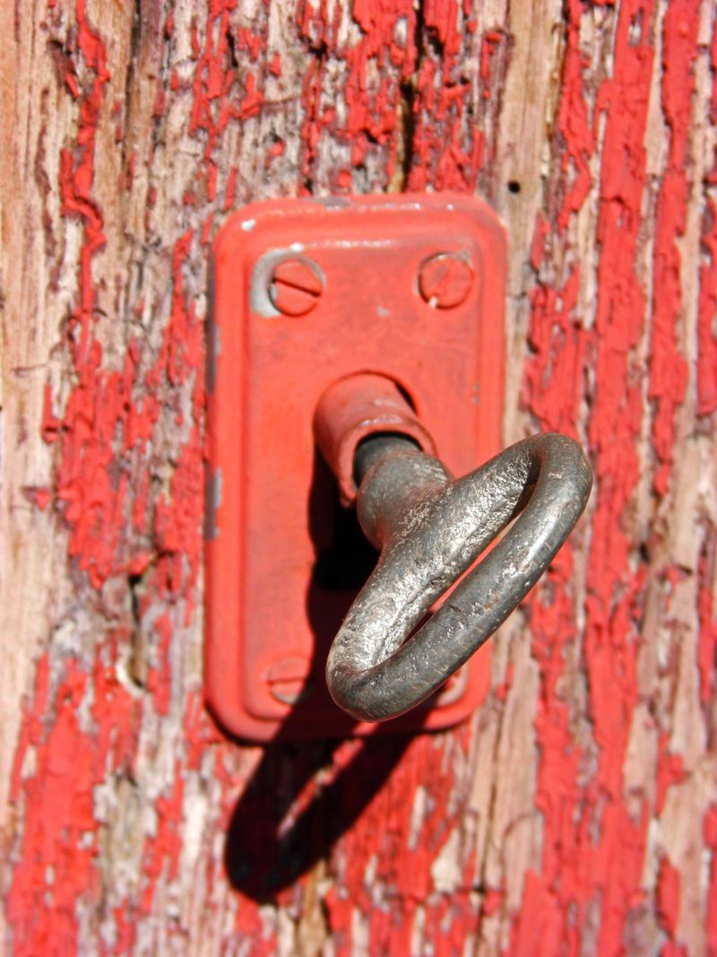 古老的铁制钥匙从门上挂在古老的红色木门上