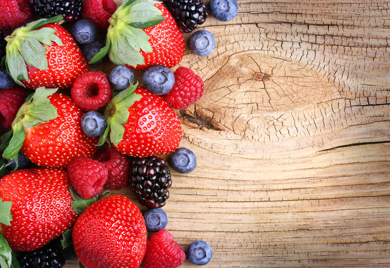 木质背景的浆果-草莓、蓝莓、覆盆子和黑莓
