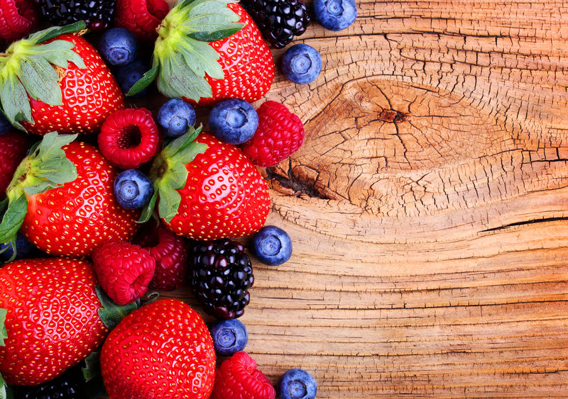 木质背景的浆果-草莓、蓝莓、覆盆子和黑莓