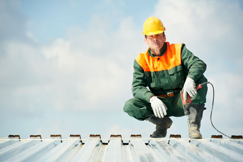在金属型材屋顶安装时使用手钻的施工人员