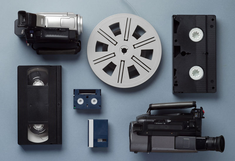 摄像机、VHS和微型磁带以及一卷胶卷-布置在蓝色背景上-俯视图
