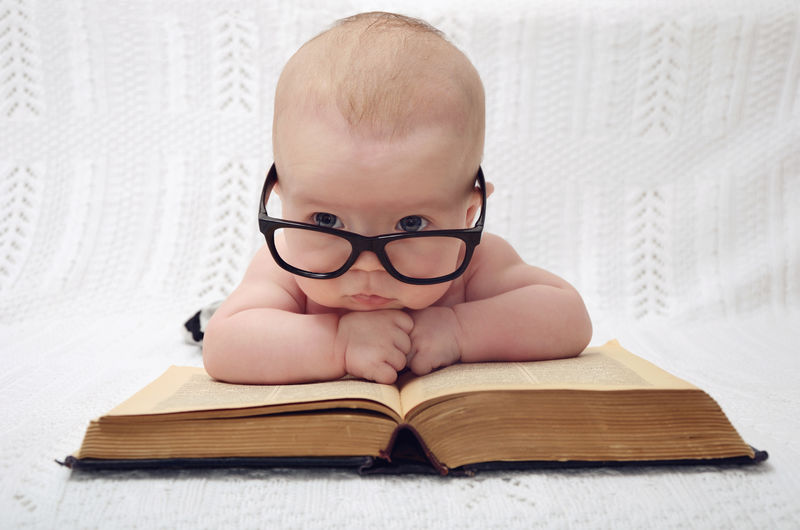 一本旧书（复古风格）上戴着眼镜的可爱婴儿的有趣画像