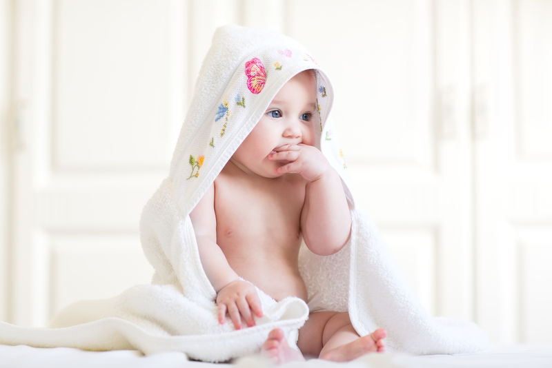 洗完澡坐在带帽毛巾下的可爱女婴