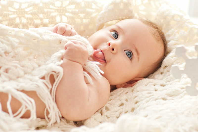 可爱的小女孩的肖像-蓝色的眼睛在她舒适的白色床上