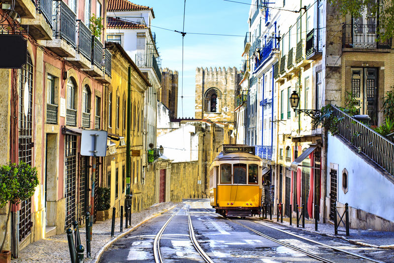 以典型的黄色电车和里斯本大教堂为背景的浪漫Lisbon街