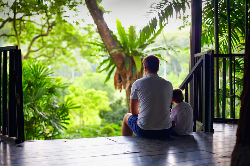 父亲和儿子坐在热带森林的树屋楼梯上