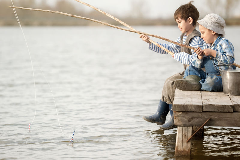 小男孩在湖边日落时钓鱼