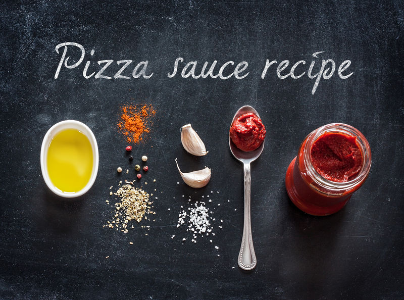 在黑色背景下的比萨酱配料或配方-番茄酱-橄榄油-大蒜-牛至-盐和胡椒粉从上面煮食物