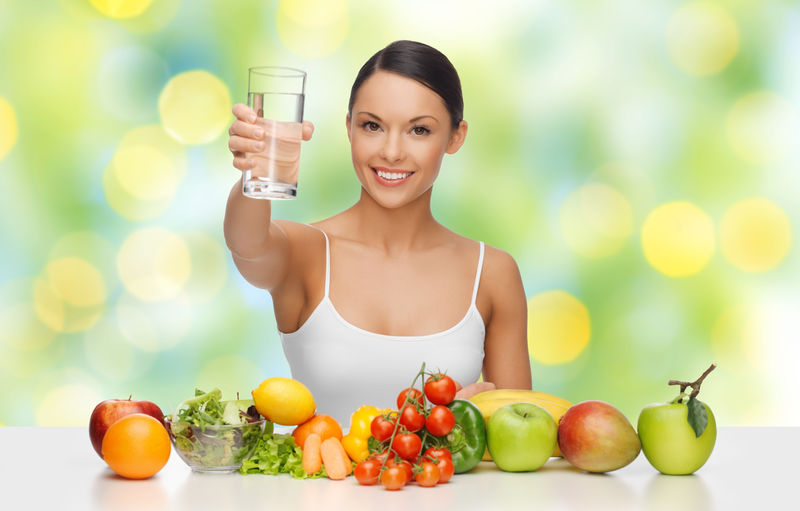 有健康食物的快乐女人展示水杯。