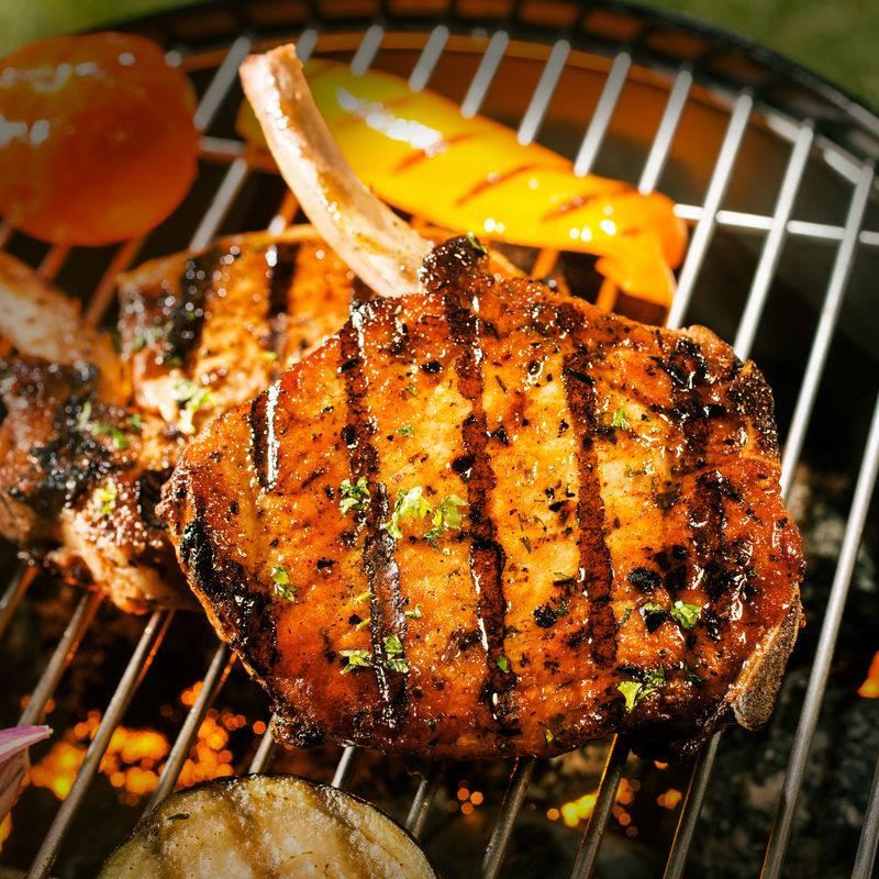 美味的脆皮烤肉、腌制和调味猪腰肉、茄子和番茄在烤架上烹饪-近距离观看肉类