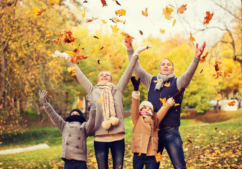 家庭、童年、季节和人的观念——快乐的家庭在公园里玩秋叶