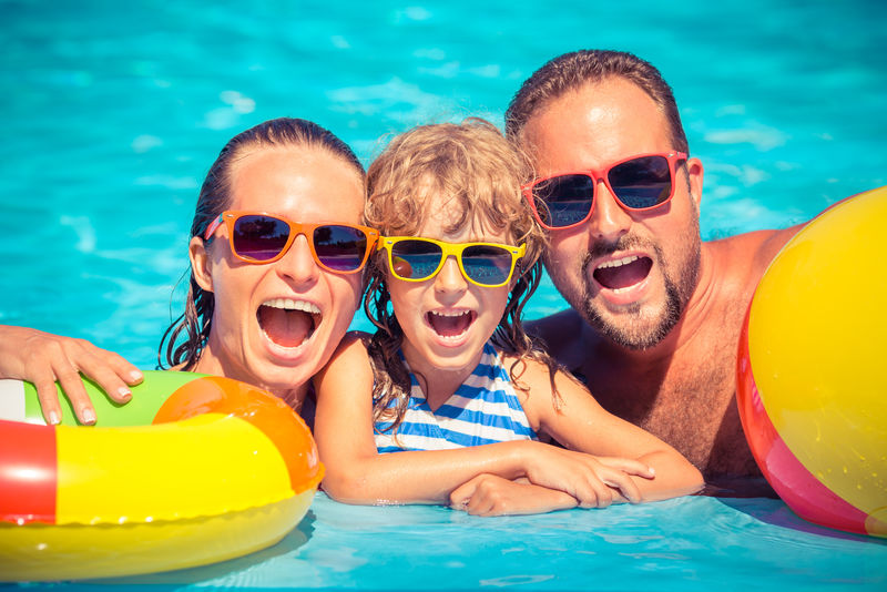 快乐的一家人在游泳池里玩耍-暑假概念