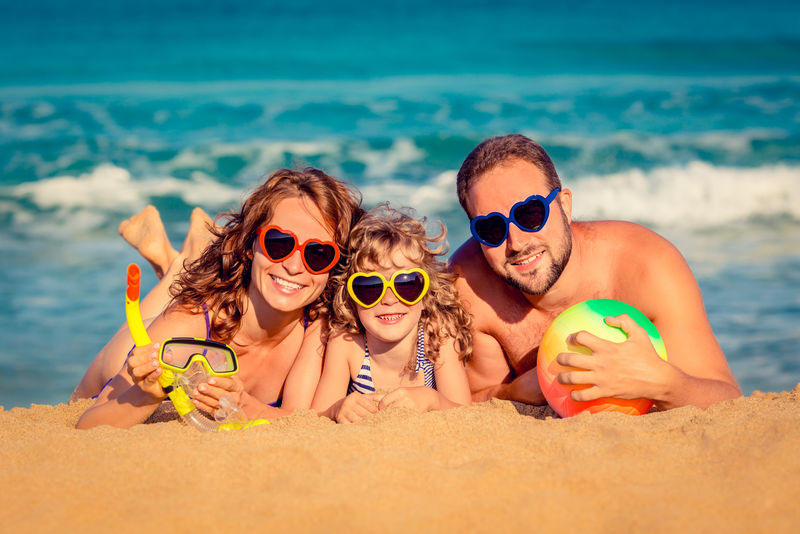 在海滩玩耍的快乐家庭-暑假的概念