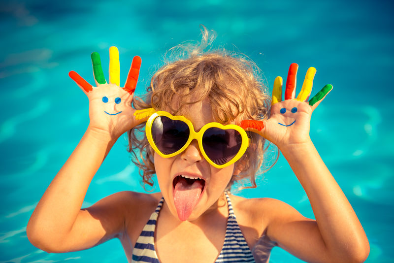 在游泳池里用手画笑脸的有趣的孩子-暑假概念