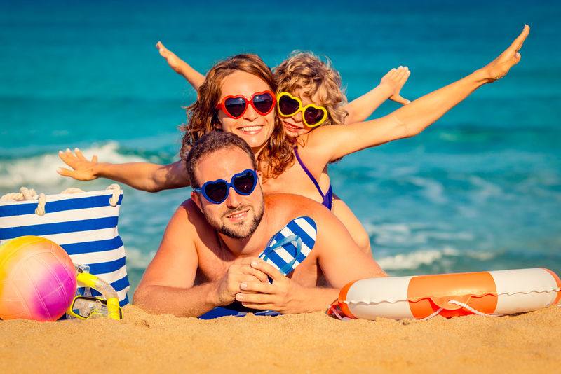 在海滩玩耍的快乐家庭-暑假的概念
