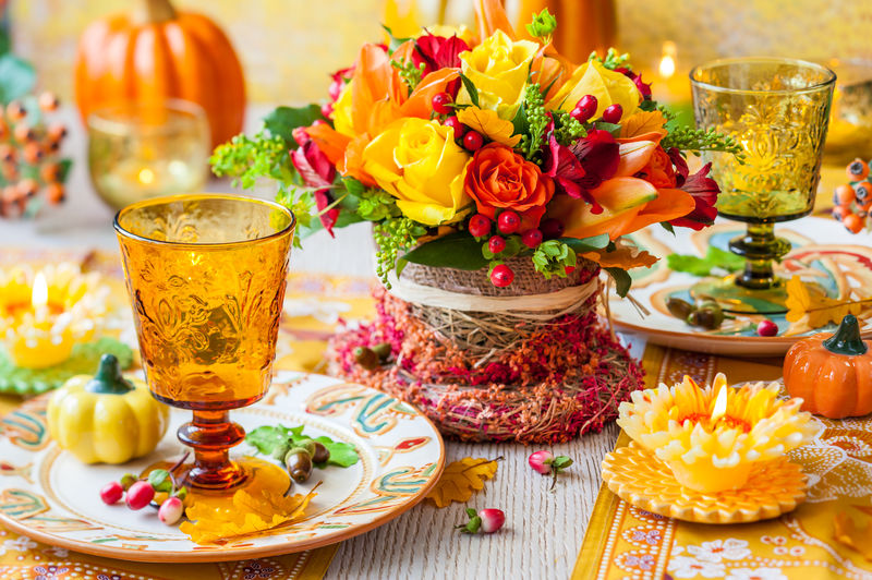 盛开秋花、蜡烛和南瓜的节日餐桌