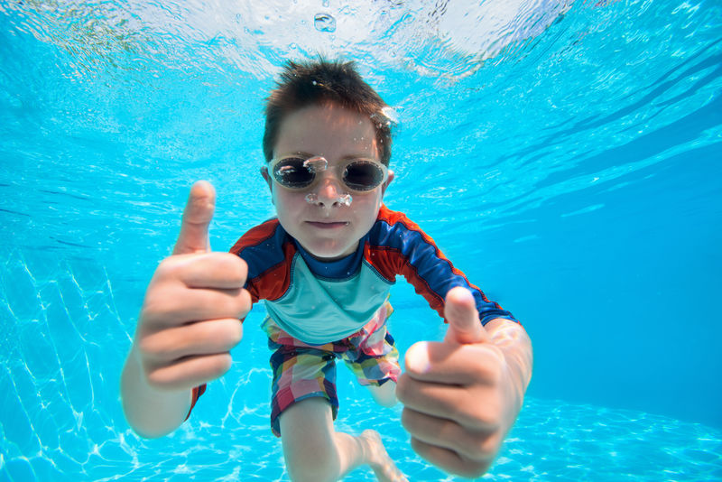一个可爱的小男孩在水下游泳的照片