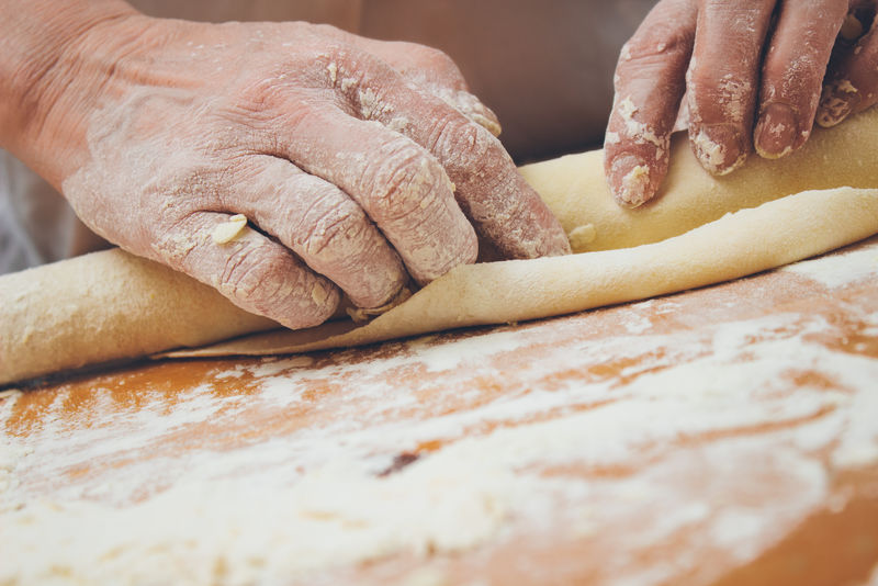 面包师用擀面杖捏面团的特写照片-复古风格的图像-添加的谷物