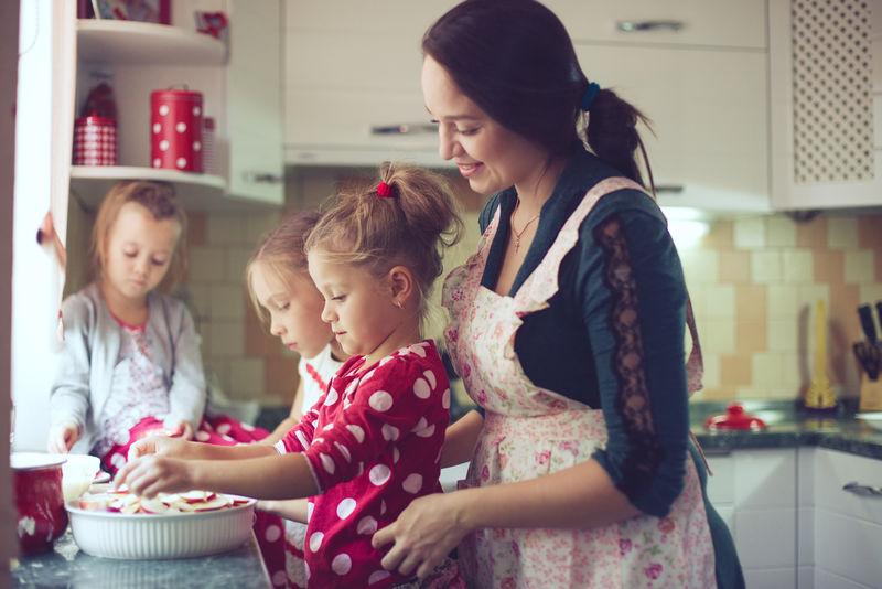 带着三个孩子的母亲在厨房里做节日派-在现实生活中拍摄休闲生活系列照片