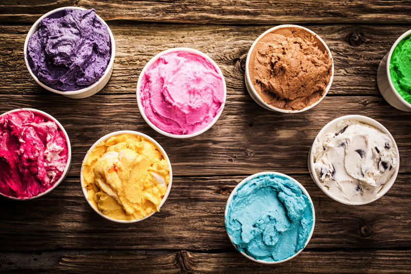 精选的意大利风味的冰淇淋在一个古老的乡村木制桌子上的冰淇淋店-架空视图在鲜艳的色彩-服务于个别塑料桶