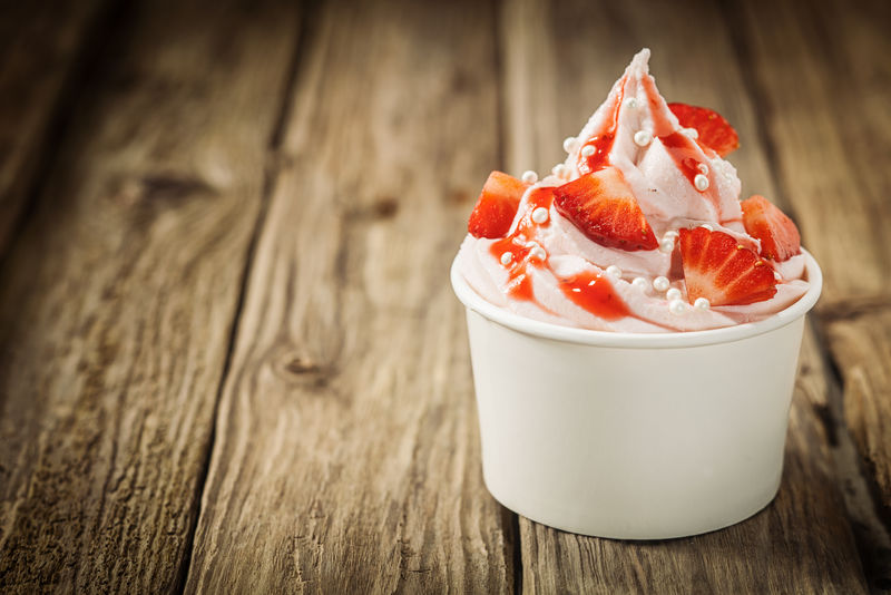 健康、新鲜、成熟的草莓放在一桶奶油冻酸奶上-撒上装饰性的糖珍珠-在阳光下享受清爽的夏日佳肴