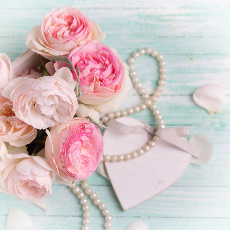 木盆里的粉红玫瑰、装饰性的心形图案和绿松石背景上的珍珠-选择性聚焦-方形图像