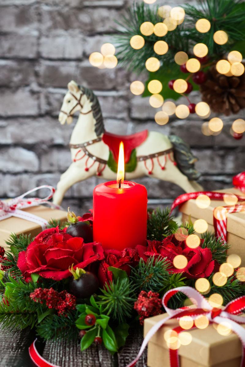 圣诞装饰品-红烛-礼品盒和摇摆木马放在旧木桌上